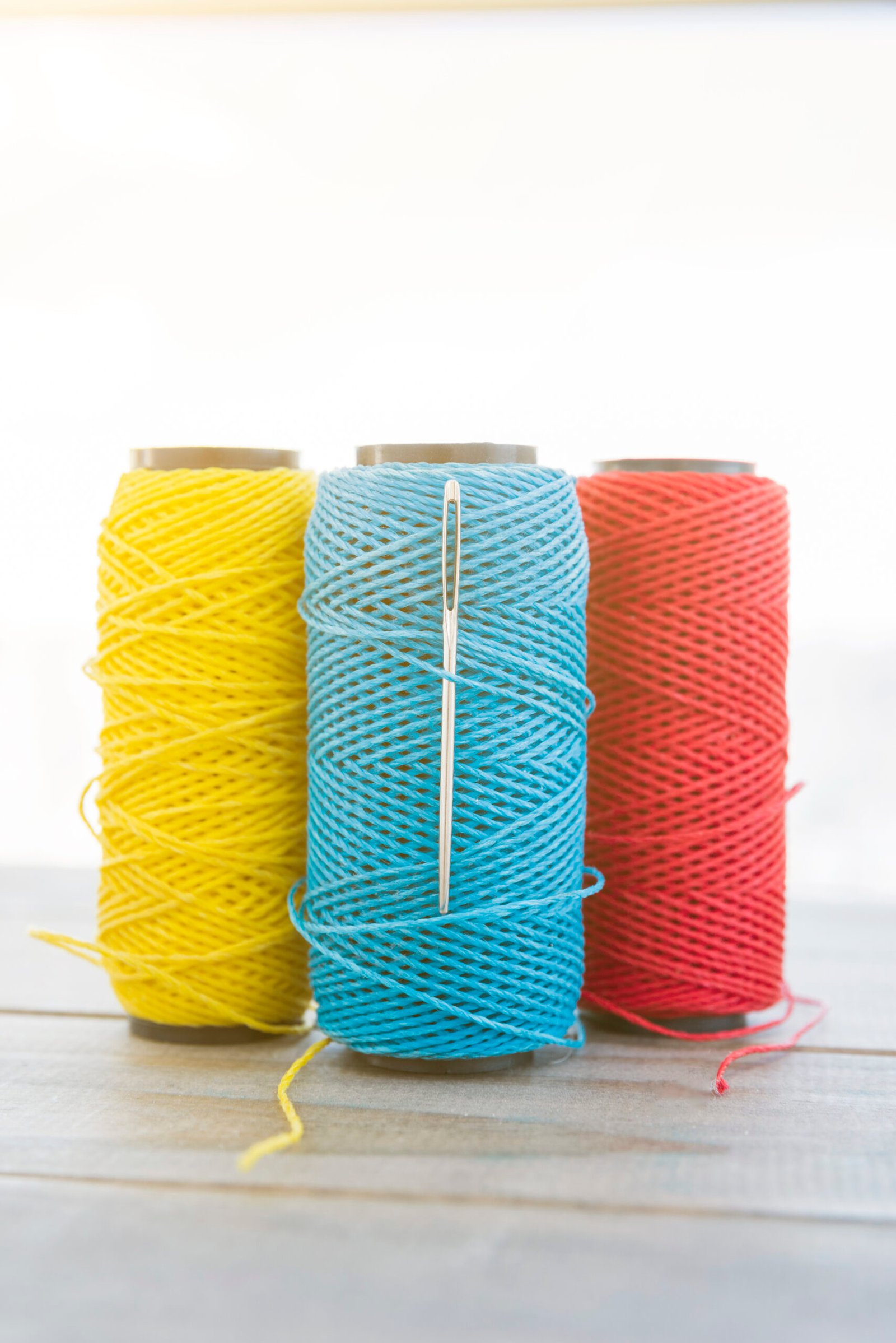 yellow-blue-red-yarn-spool-wooden-desk